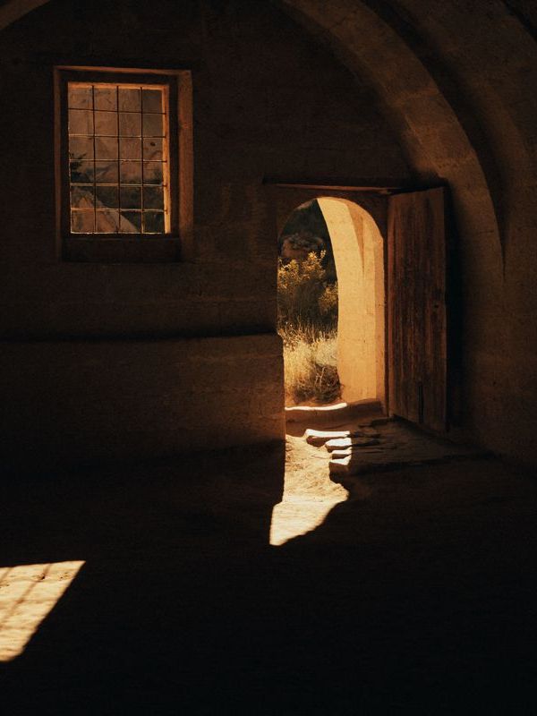 A thick stone arch opening onto a sunlit whitewashed courtyard